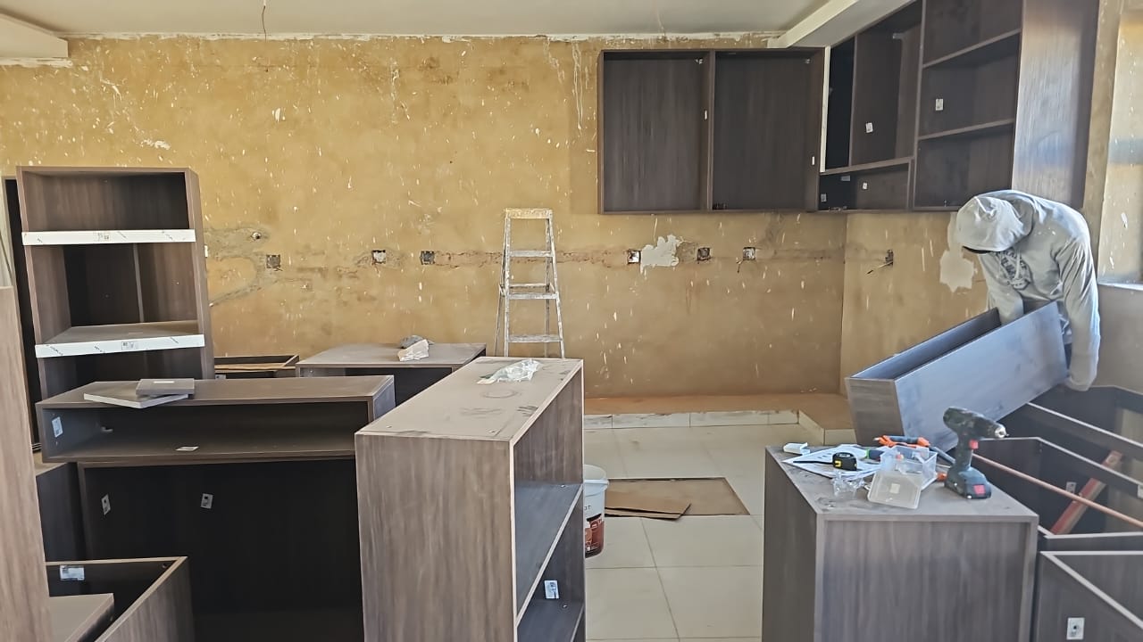 On-site assembly of walnut-tone wardrobe cabinets and drawer units