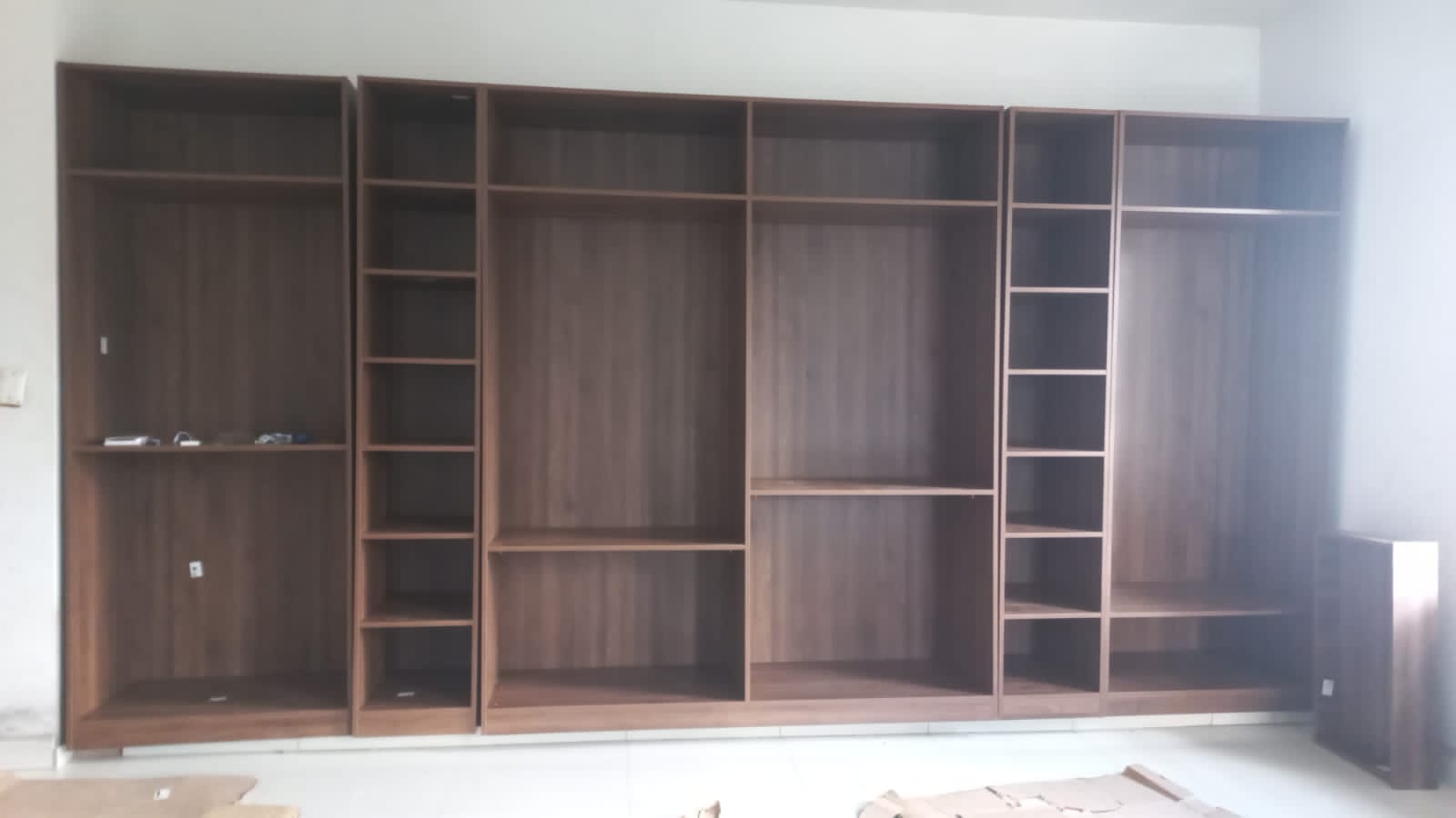 Wall-to-wall walnut-tone wardrobe carcasses before door installation