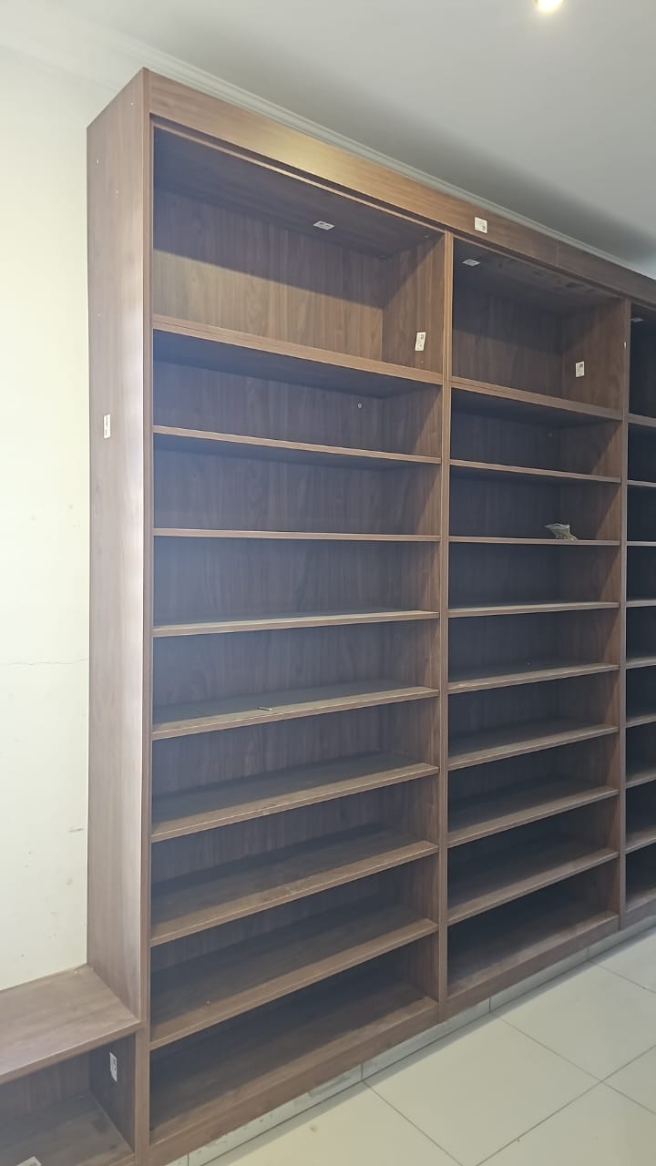 Tall walnut-tone open-shelf wardrobe unit during installation