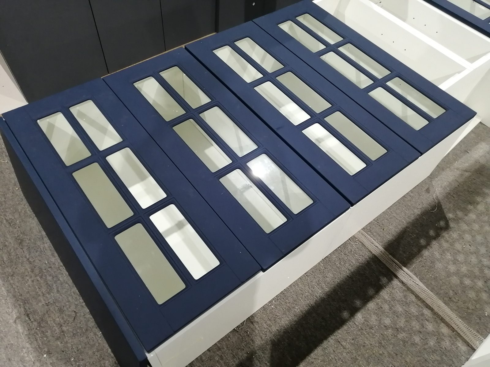 Factory test installation of navy blue glass-front cabinet doors before packing